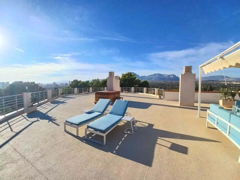 La azotea: dos tumbonas con cojines azules, un jacuzzi de madera y la sierra al fondo.